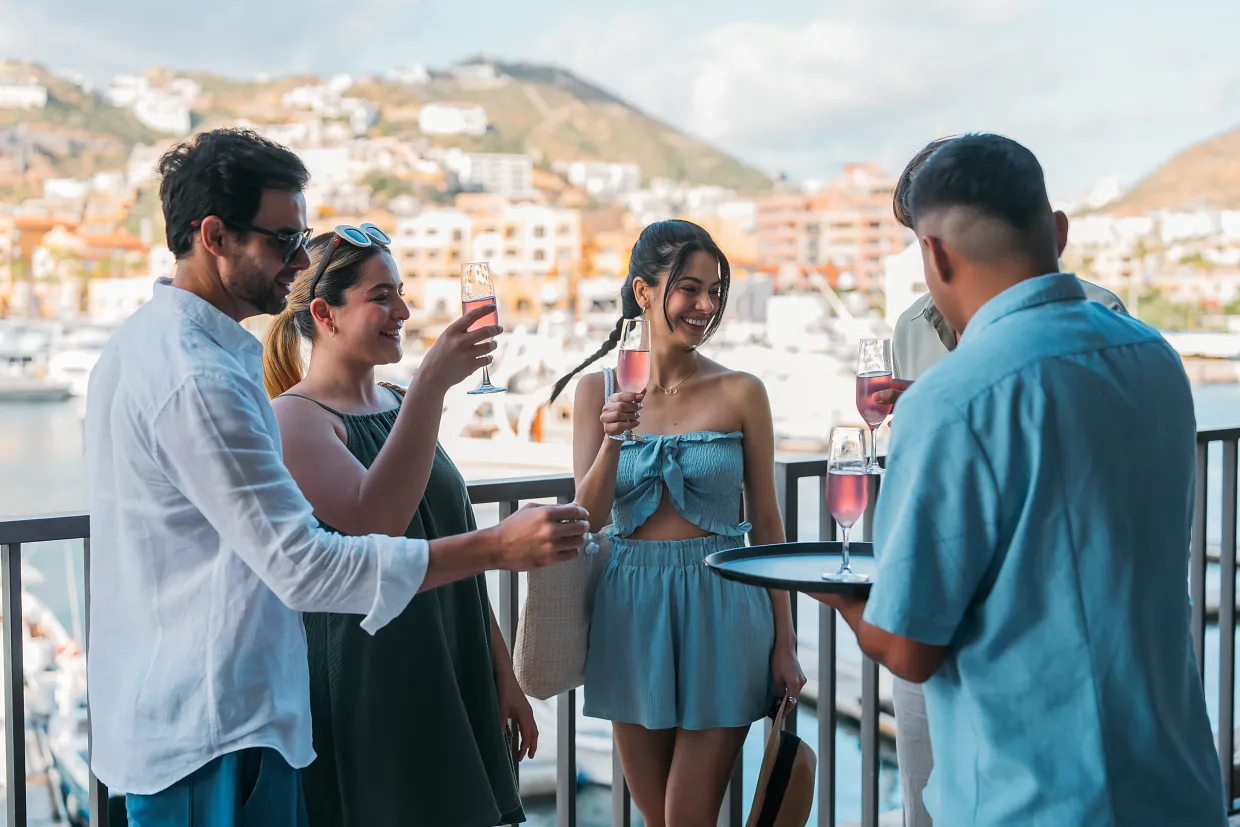 Guests enjoying welcome drinks on a marina-view terrace at Breathless Cabo San Lucas Resort.
