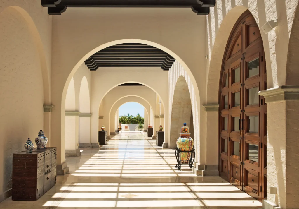 Elegant arched corridor with natural light and Mexican decor at Secrets Puerto Los Cabos resort.