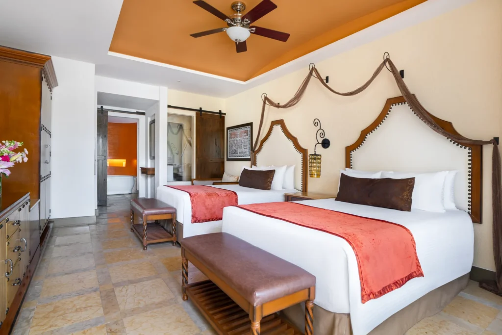 Junior Suite Garden View with two double beds and sitting area at Secrets Puerto Los Cabos Golf & Spa Resort.