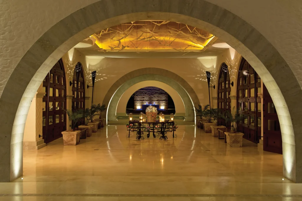 Grand lobby with arched architecture and soft lighting at Secrets Puerto Los Cabos.
