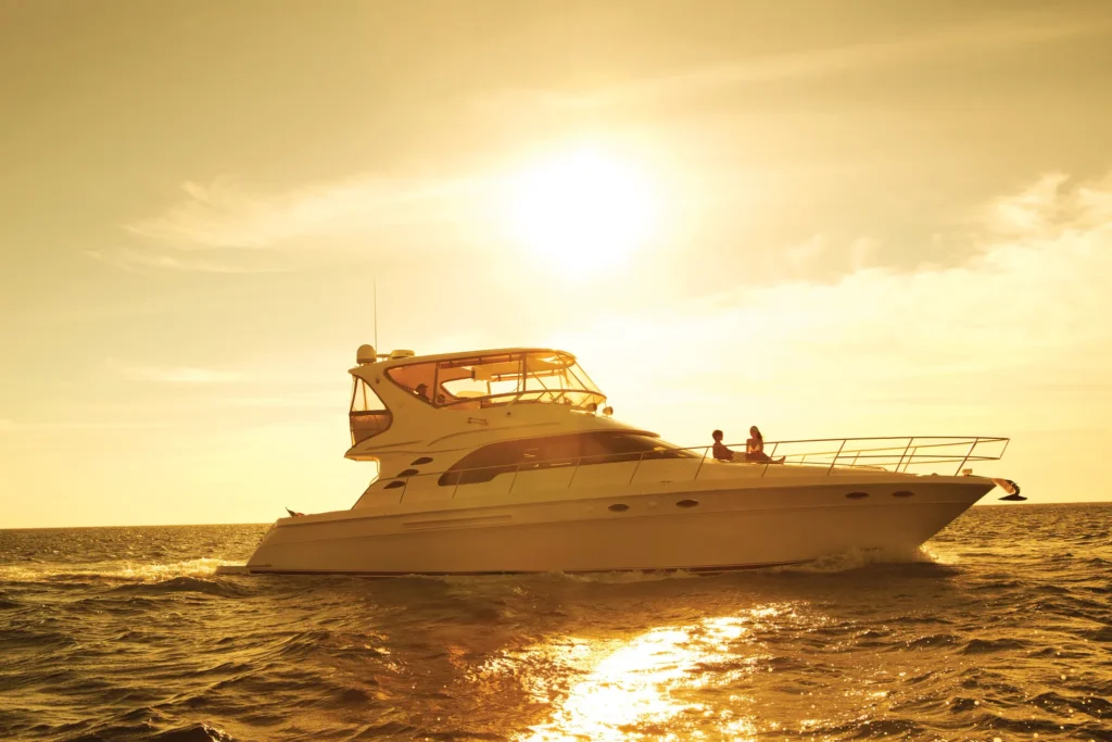 Luxury yacht sailing at sunset near Secrets Puerto Los Cabos Golf & Spa Resort.