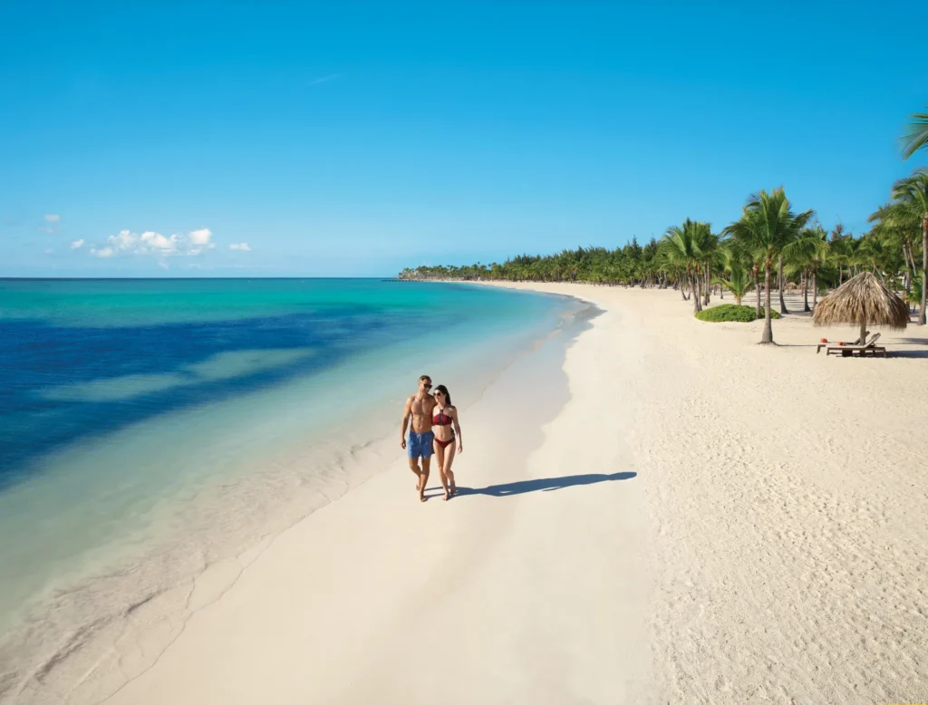 Couple enjoying a romantic stroll along the white-sand beach at Secrets Cap Cana Resort & Spa in Punta Cana.
