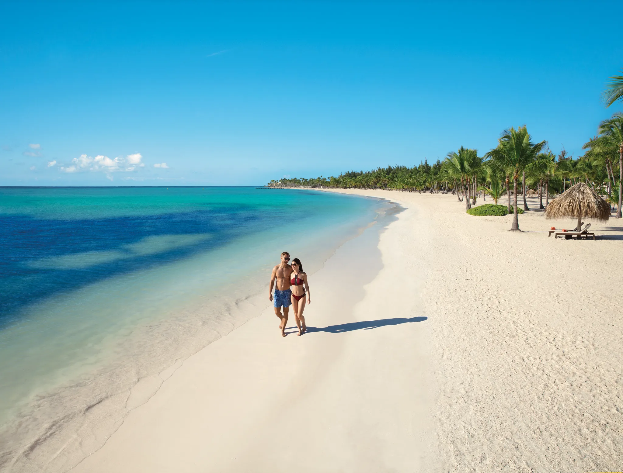 Couple enjoying a romantic stroll along the white-sand beach at Secrets Cap Cana Resort & Spa in Punta Cana.