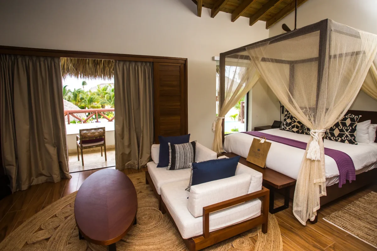 Preferred Club Bungalow Master Suite Pool View with king-size canopy bed, sitting area, furnished balcony, and luxury Caribbean décor.