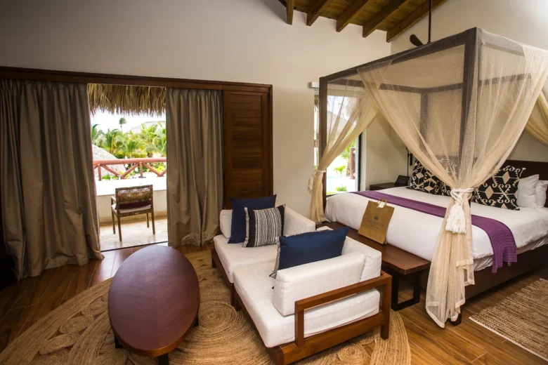 Preferred Club Bungalow Master Suite Pool View with king-size canopy bed, sitting area, furnished balcony, and luxury Caribbean décor.