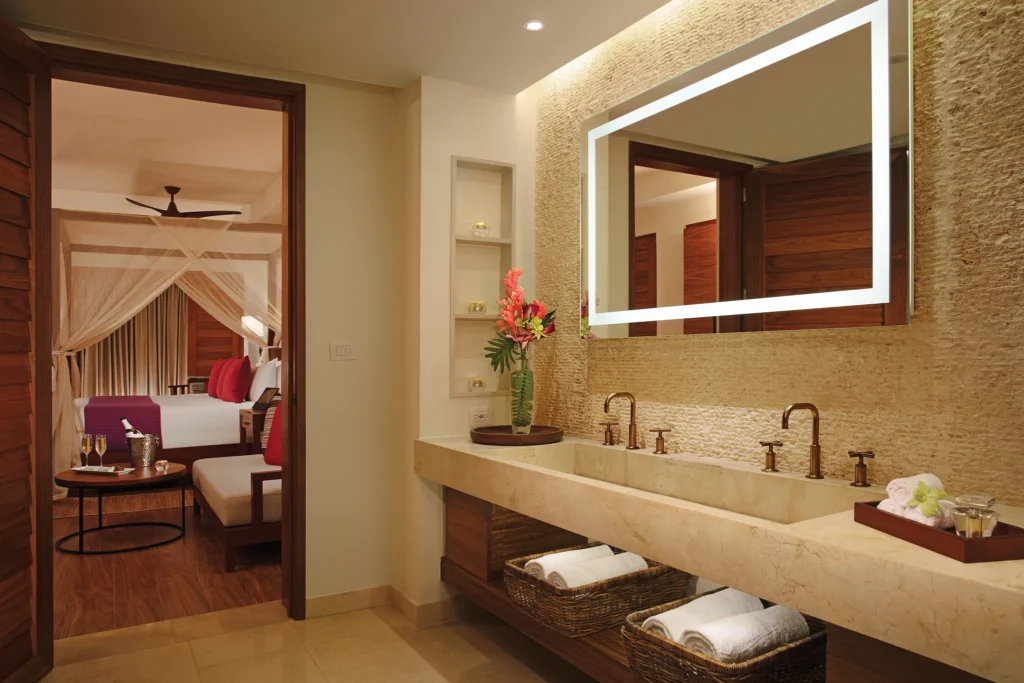 Preferred Club Bungalow Suite Swim Out Ocean Front bathroom with illuminated mirror, double vanity, and upscale natural stone finishes.