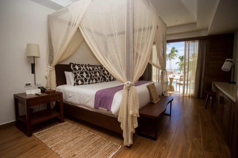 Preferred Club Bungalow Suite Swim Out Ocean Front bedroom with king-size canopy bed, hardwood flooring, and oceanfront terrace access.