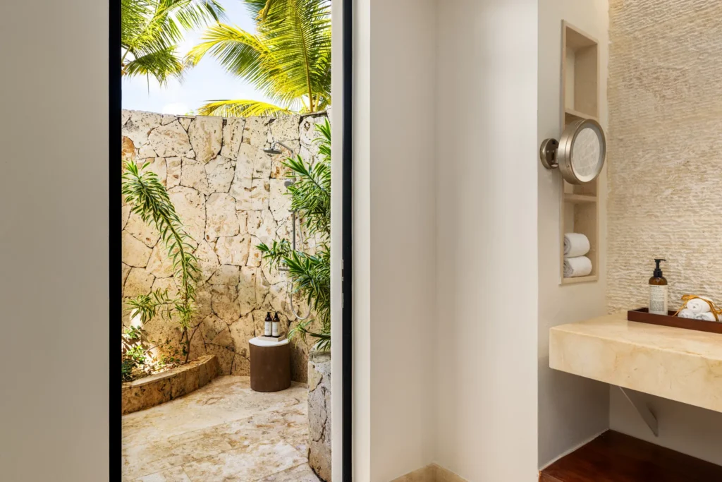 Preferred Club Bungalow Suite Swim Out Ocean Front bathroom with illuminated mirror, double vanity, and upscale natural stone finishes.