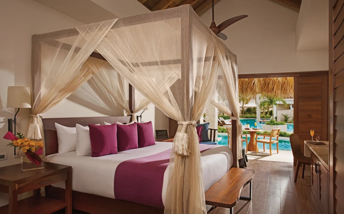 Preferred Club Bungalow Suite Swim Out Pool View bedroom with king-size canopy bed, pool access, and luxury Caribbean décor.