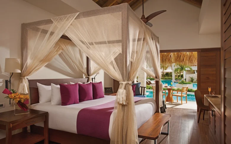 Preferred Club Bungalow Suite Swim Out Pool View bedroom with king-size canopy bed, pool access, and luxury Caribbean décor.