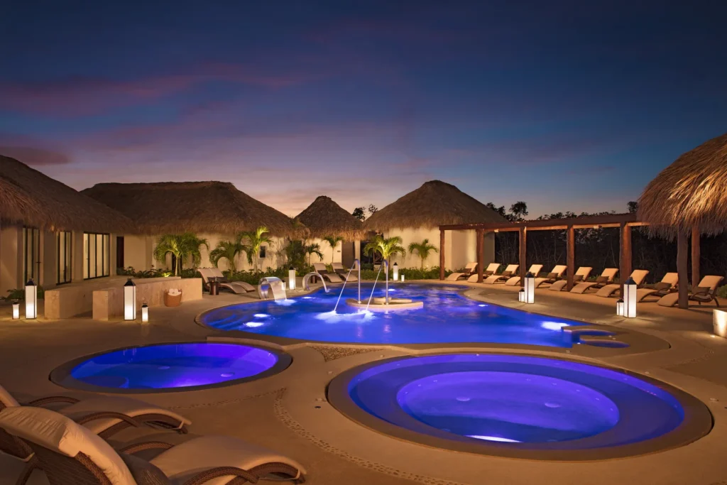 Illuminated hydrotherapy pools at night at Secrets Cap Cana Resort & Spa, creating a peaceful luxury spa atmosphere in Punta Cana.