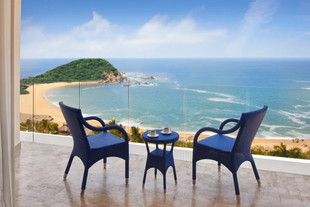 Private oceanfront balcony with seating overlooking the beach and Pacific Ocean at Secrets Huatulco Resort & Spa.
