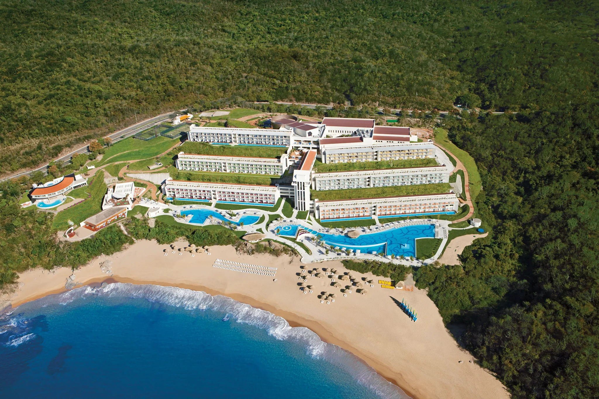 Secrets Huatulco Resort & Spa adults-only all-inclusive with beachfront infinity pools, lush mountains, and Pacific Ocean views in Oaxaca, Mexico.