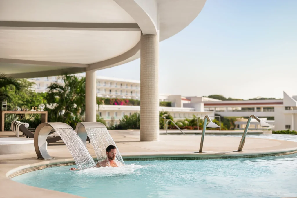 Guest unwinding in the outdoor spa pool at Secrets Huatulco Resort & Spa, featuring modern design and lush surroundings.