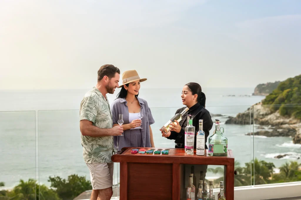Guests enjoying a guided mezcal tasting with ocean views at Secrets Huatulco Resort & Spa in Mexico.