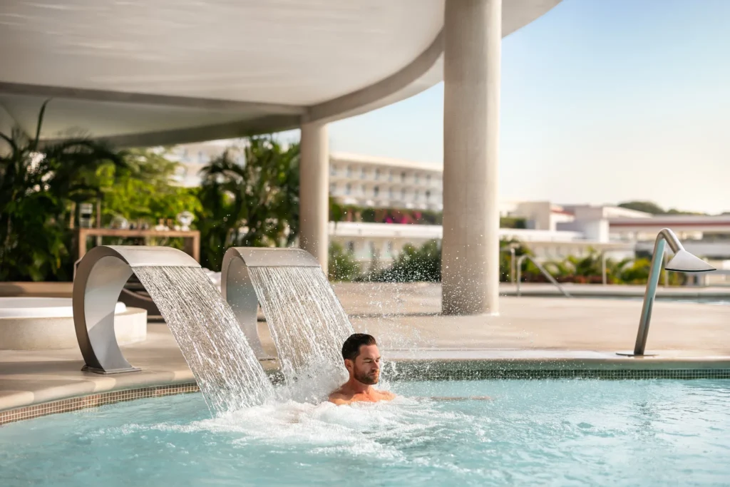 Man enjoying a hydrotherapy waterfall pool at Secrets Huatulco Resort & Spa, part of the adults-only luxury spa experience.