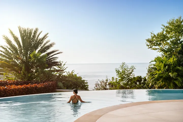 Guest enjoying the infinity pool at Secrets Huatulco Resort & Spa with panoramic ocean views and a peaceful adults-only ambiance.