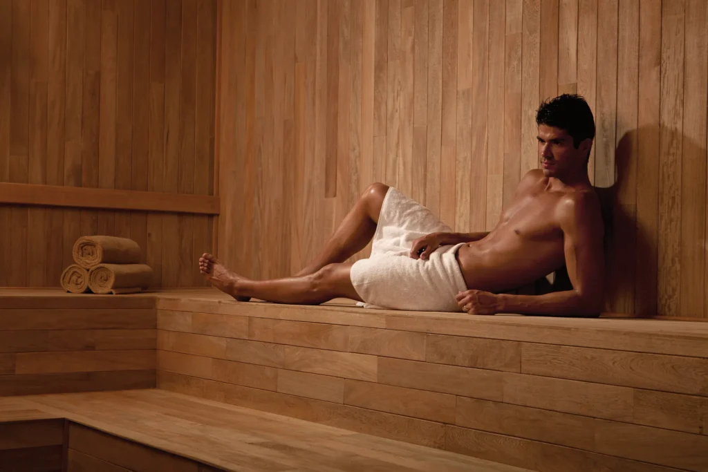 Guest relaxing inside a wood-lined sauna at Secrets Huatulco Resort & Spa, offering a calming adults-only wellness experience.