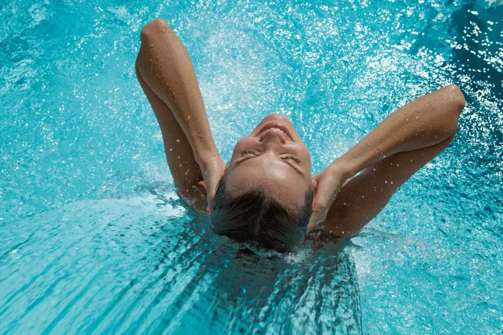 Guest enjoying a waterfall massage feature in the spa circuit pool at Secrets Huatulco Resort & Spa.