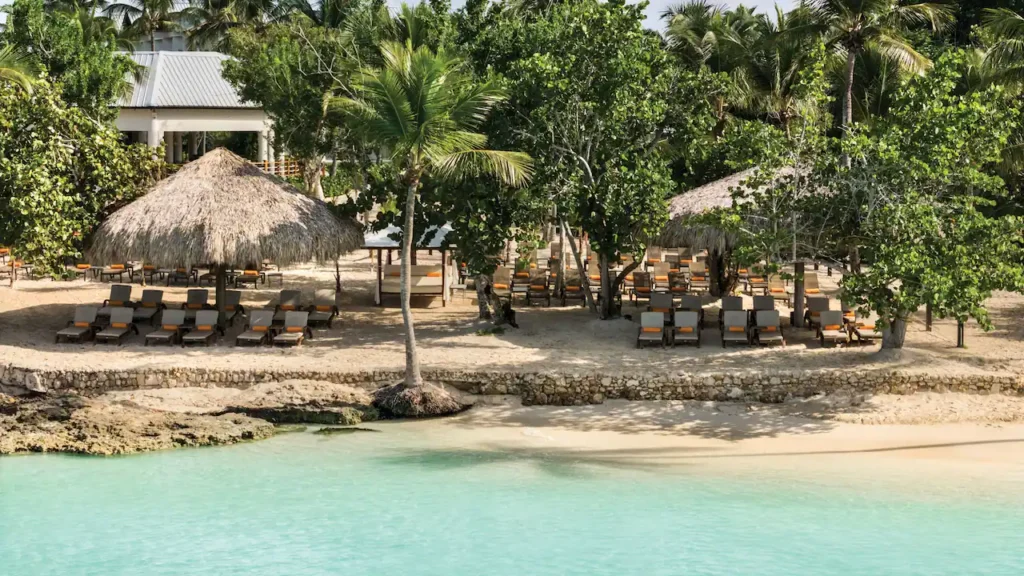 Beachfront lounge chairs and tropical palapas at Secrets La Romana Resort & Spa.