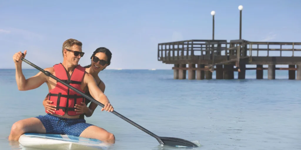 Couple paddleboarding together in calm Caribbean waters at Secrets La Romana Resort & Spa.