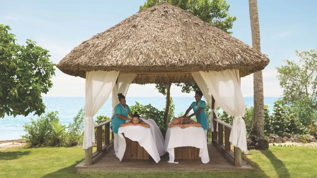 Guests enjoying beachfront massages under tropical spa palapas at Secrets La Romana Resort & Spa.