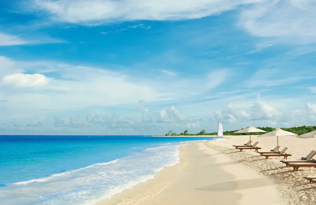 Beach loungers and umbrellas on Maroma Beach with turquoise Caribbean waters at Secrets Maroma Beach Riviera Cancun.