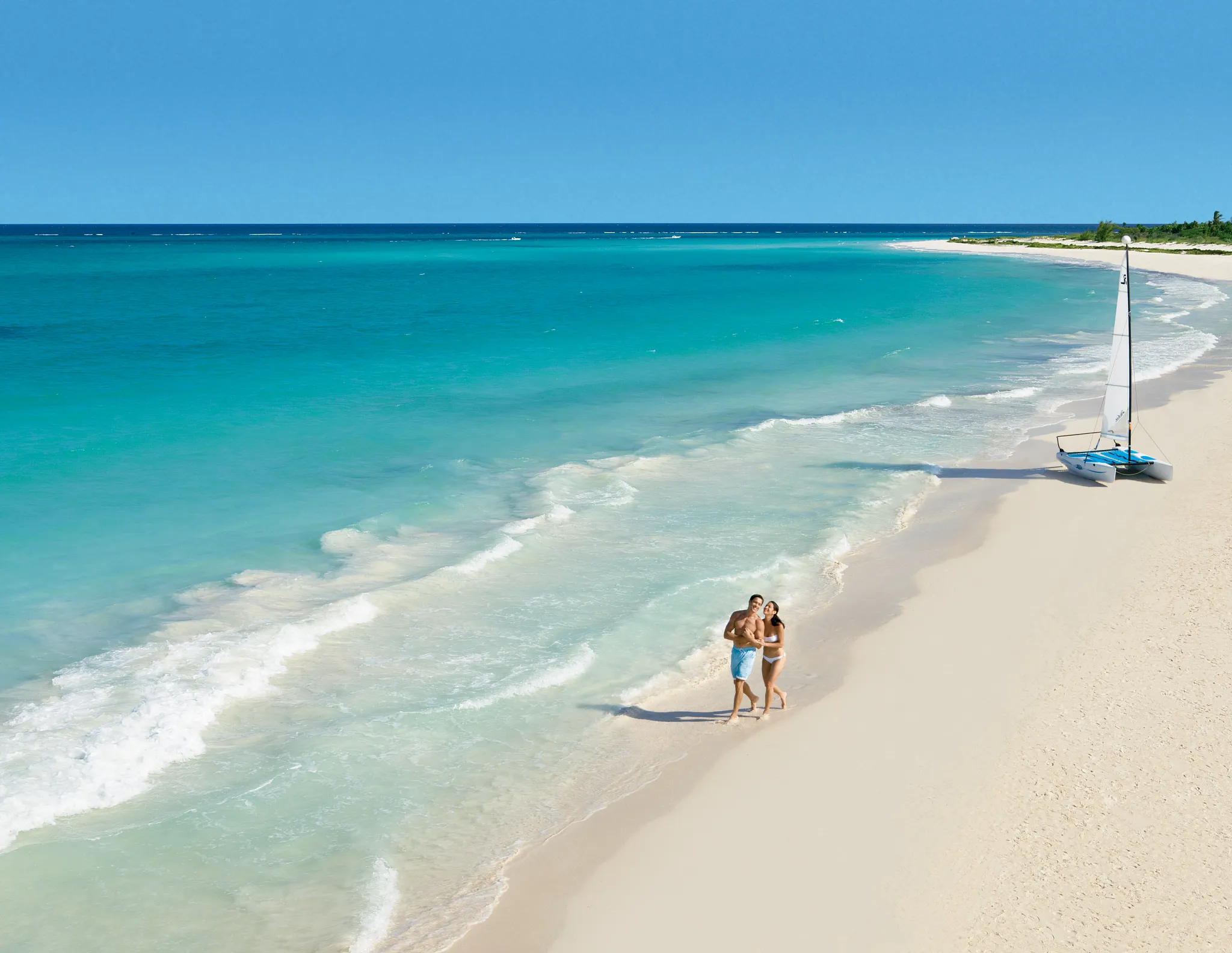 Romantic couple walking along the white-sand shores of Maroma Beach at Secrets Maroma Beach Riviera Cancun.