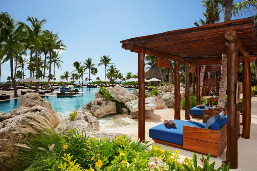 Private pool cabanas with cushioned loungers at Secrets Maroma Beach Riviera Cancun surrounded by tropical landscaping.