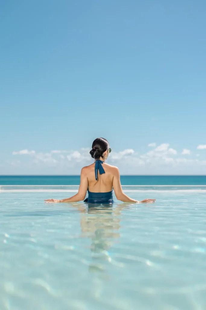Woman relaxing in an infinity pool overlooking the Caribbean Sea at Secrets Mirabel Cancun Resort & Spa.