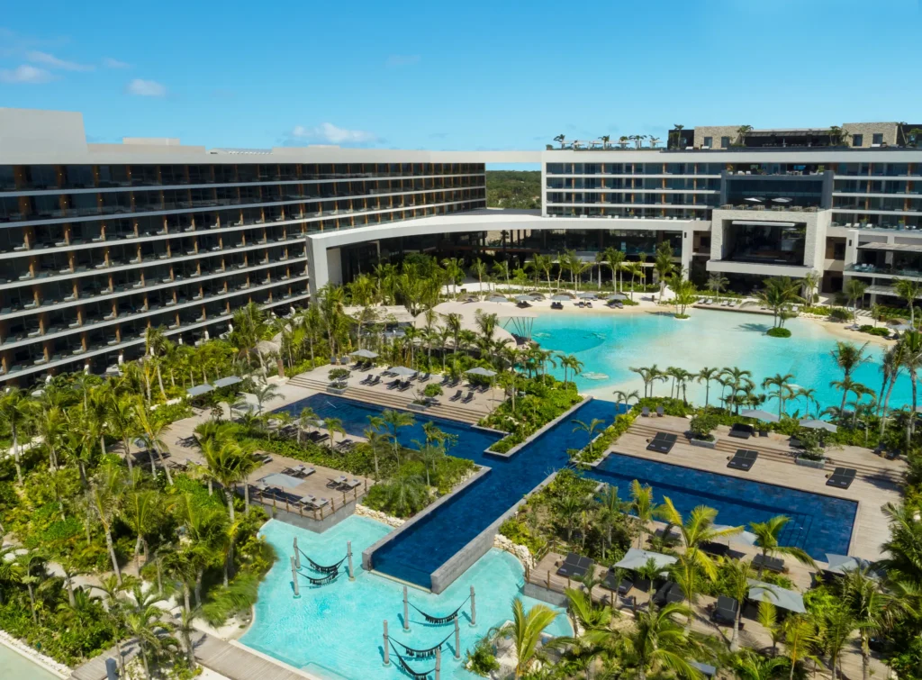 Aerial view of the cross-shaped infinity pool surrounded by tropical gardens at Secrets Moxché Playa Del Carmen, a luxury adults-only resort on the Riviera Maya.