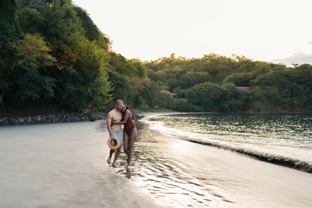 Romantic couple walking along the secluded beach at Secrets Papagayo Costa Rica, surrounded by lush tropical landscapes.