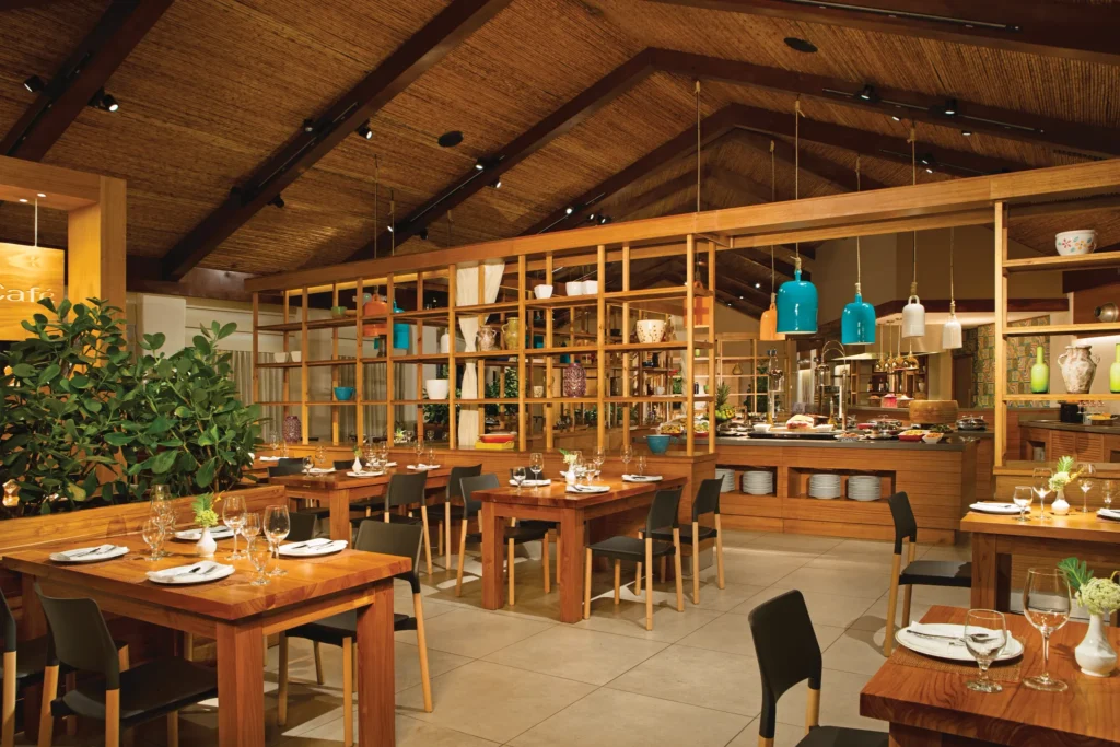 Market Café at Secrets Papagayo Costa Rica featuring a spacious open-air dining room with wooden tables, buffet stations, and warm tropical décor.