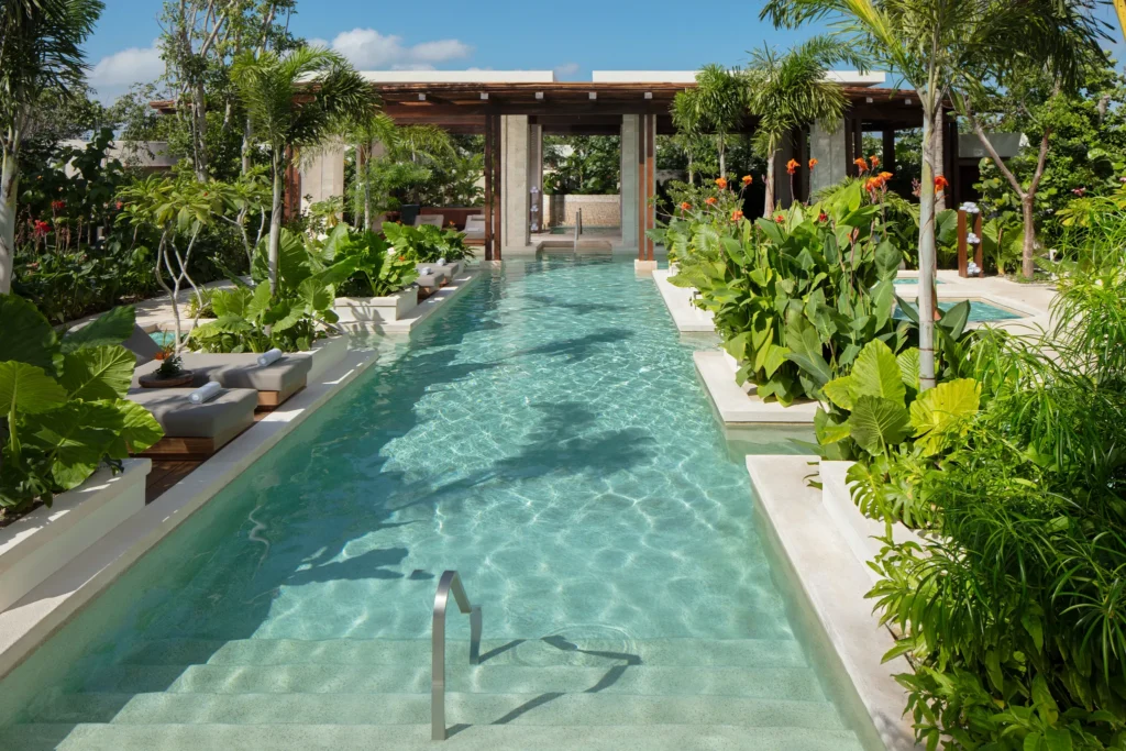 Outdoor hydrotherapy pool surrounded by lush tropical plants at Secrets Playa Blanca Costa Mujeres spa.