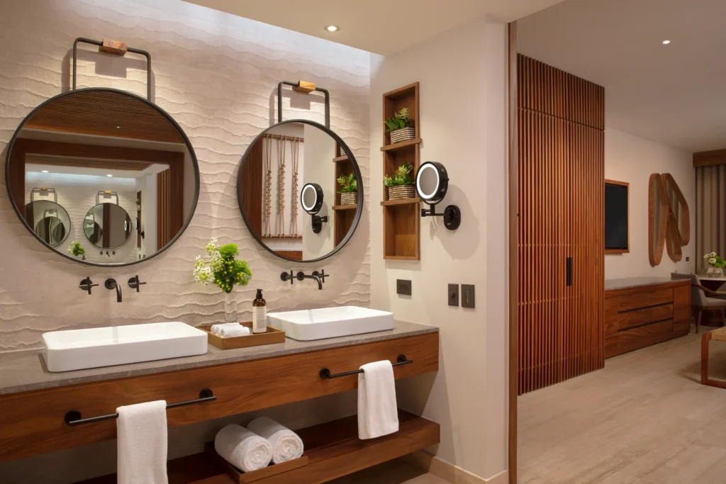 Junior Suite bathroom vanity with double sinks and round mirrors at Secrets Playa Blanca Costa Mujeres.