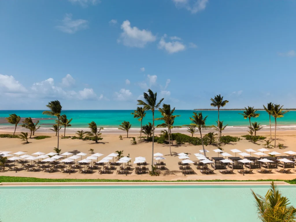 White sand beach with lounge chairs and turquoise water at Secrets Playa Esmeralda Resort & Spa.