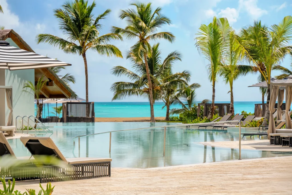 Infinity pool overlooking the ocean with palm trees at Secrets Playa Esmeralda Resort & Spa.