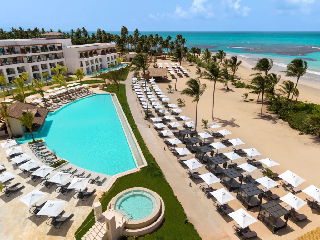 Oceanfront pool and beach lounge area with palm trees at Secrets Playa Esmeralda Resort & Spa.