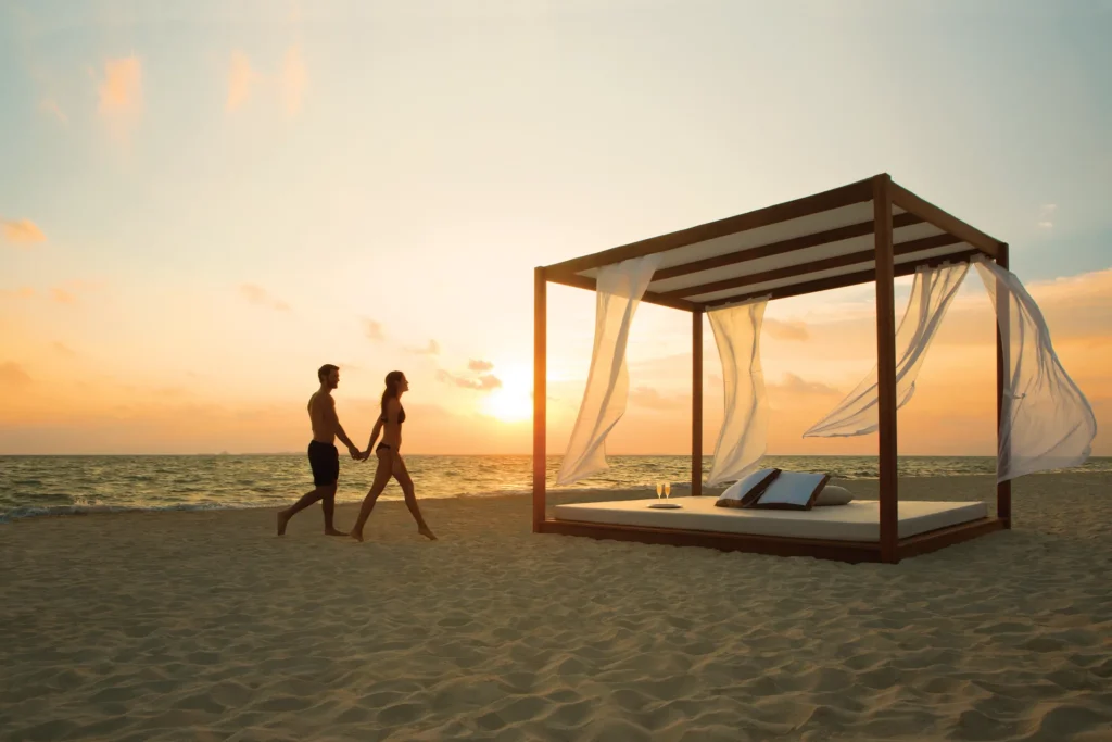 Romantic beach Bali bed setup at sunset for couples at Secrets Playa Mujeres Golf & Spa Resort.