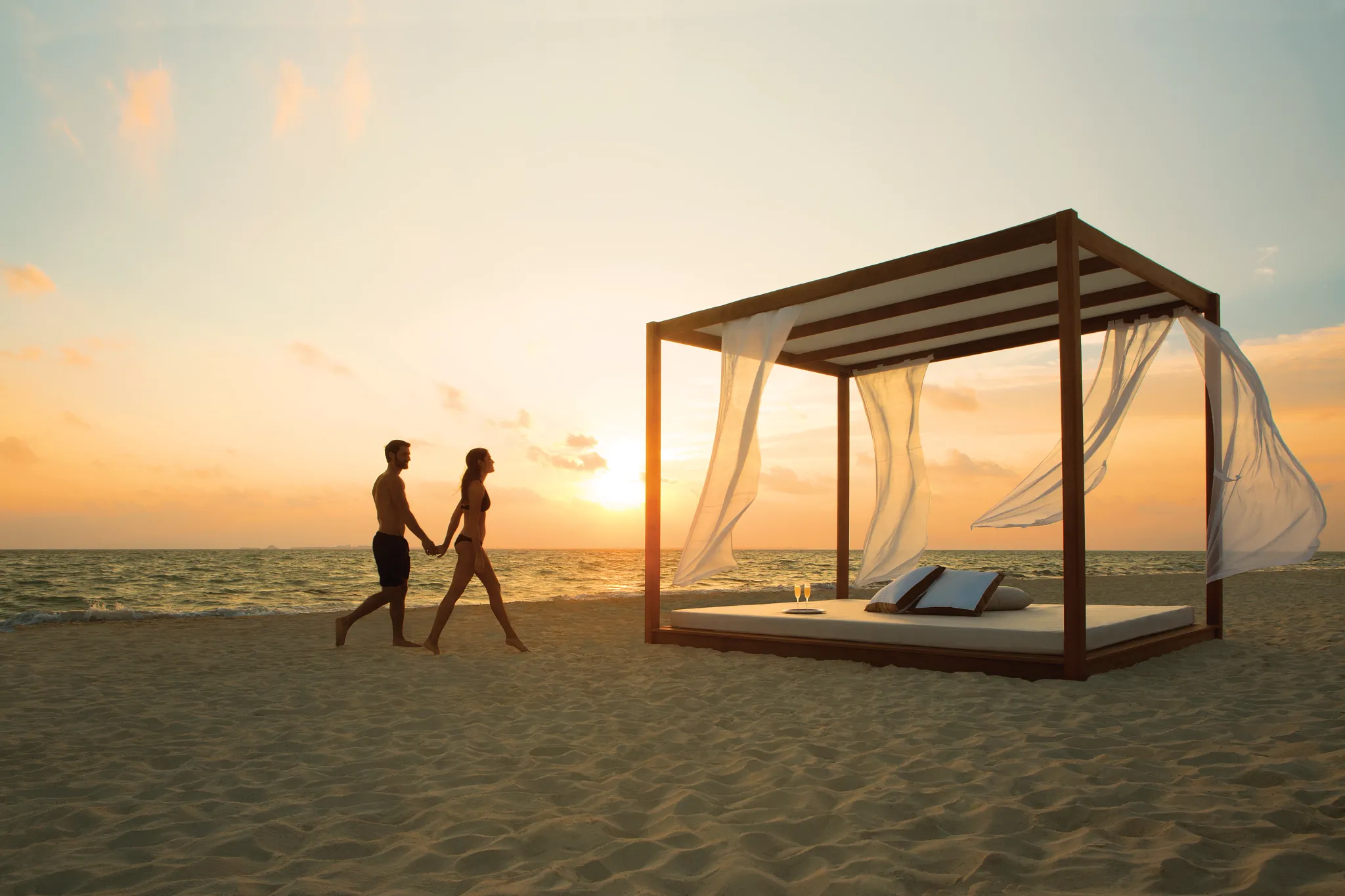 Romantic beach Bali bed setup at sunset for couples at Secrets Playa Mujeres Golf & Spa Resort.