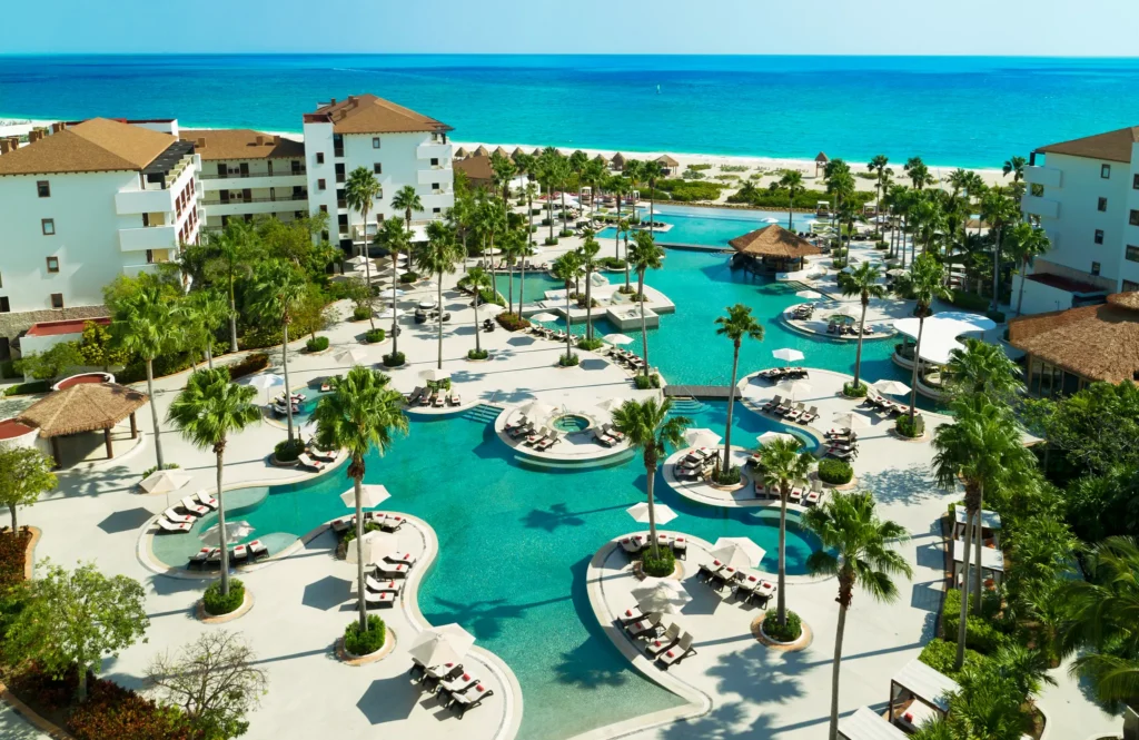 Guests relaxing beside the large resort pool surrounded by tropical landscaping at Secrets Playa Mujeres Golf & Spa Resort.