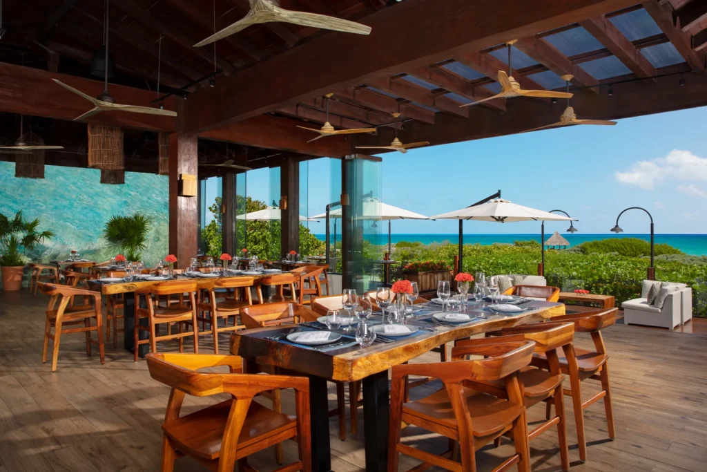 Oceana seafood restaurant at Secrets Playa Mujeres Golf & Spa Resort featuring open-air oceanfront dining with wooden tables and Caribbean Sea views.