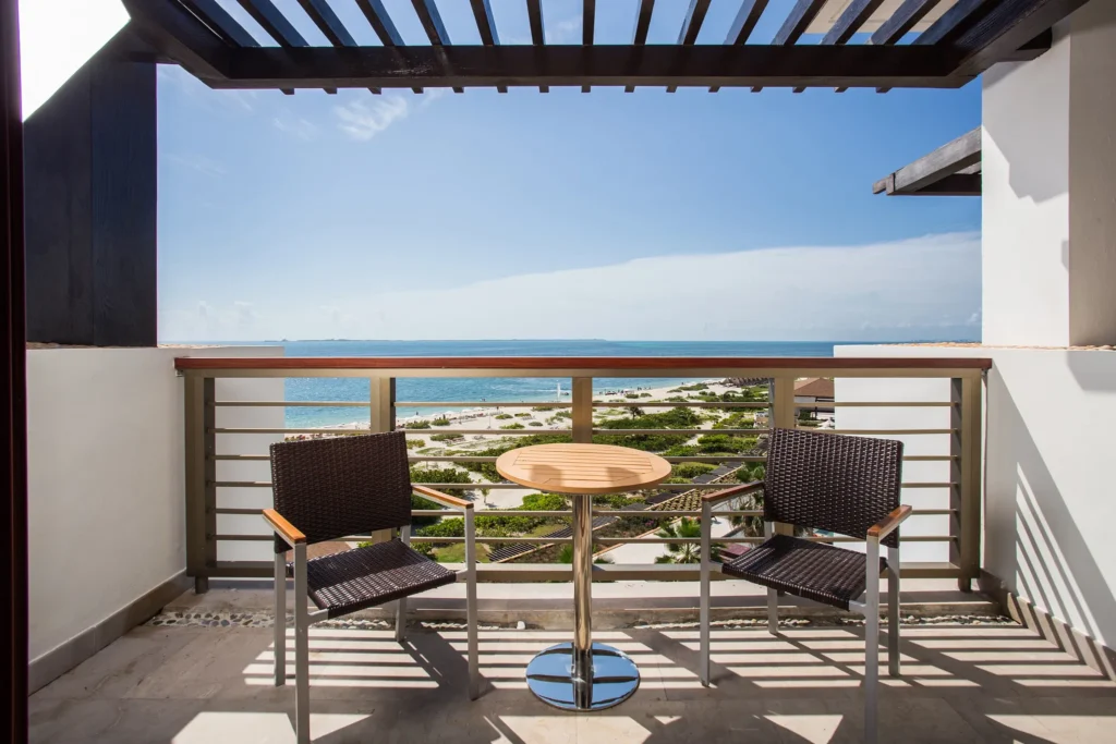 Junior Suite Ocean View private balcony with table, chairs, and Caribbean Sea views at Secrets Playa Mujeres Golf & Spa Resort.