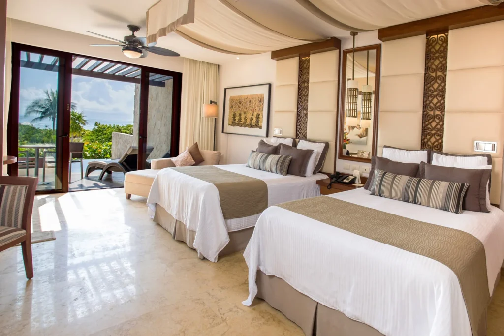 Preferred Club Junior Suite Ocean Front with two double beds and balcony at Secrets Playa Mujeres Golf & Spa Resort.