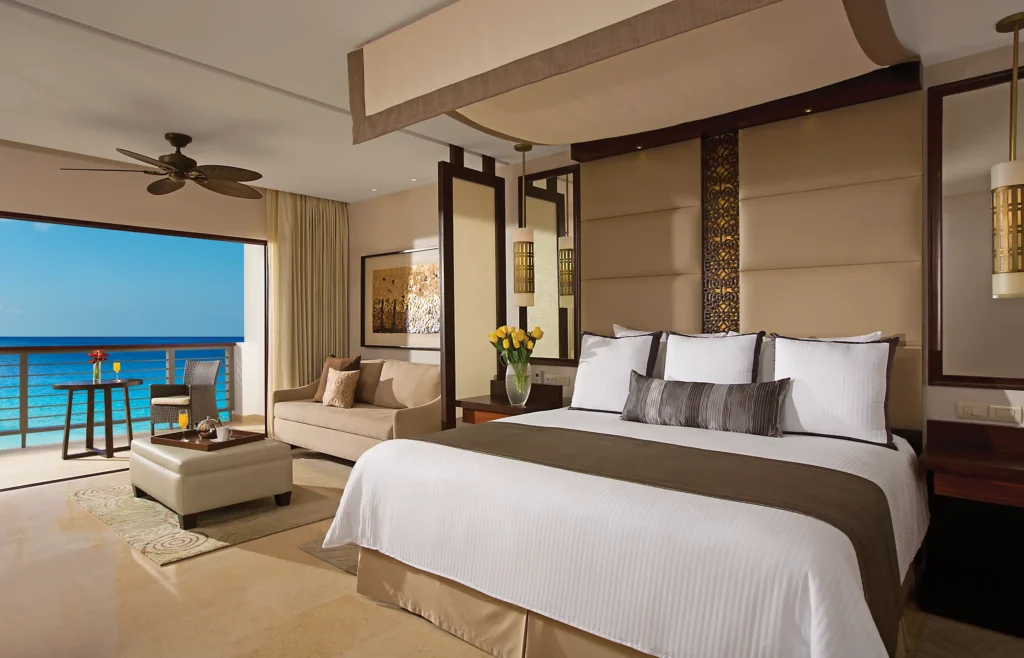 Preferred Club Junior Suite Ocean Front king suite with sitting area and ocean-view balcony at Secrets Playa Mujeres Golf & Spa Resort.