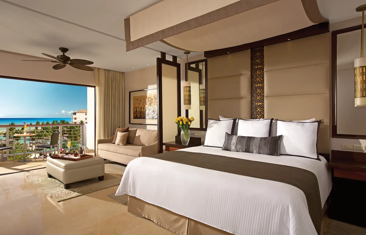 Preferred Club Junior Suite Ocean View king bedroom with seating area and private balcony at Secrets Playa Mujeres Golf & Spa Resort.