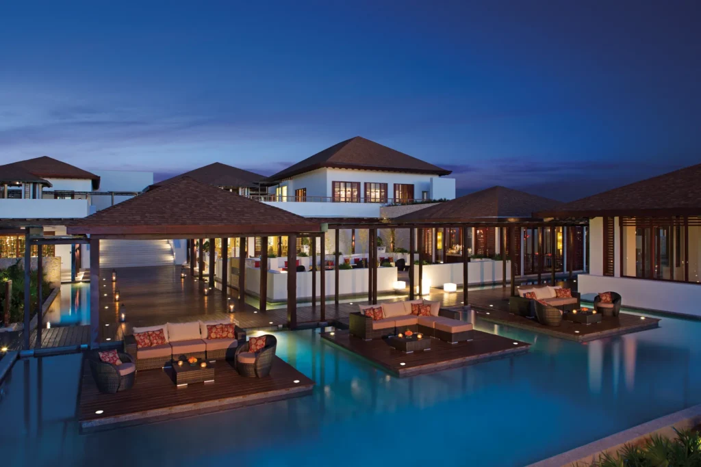 Outdoor restaurant and lounge terraces over water at night at Secrets Playa Mujeres Golf & Spa Resort in Cancun.