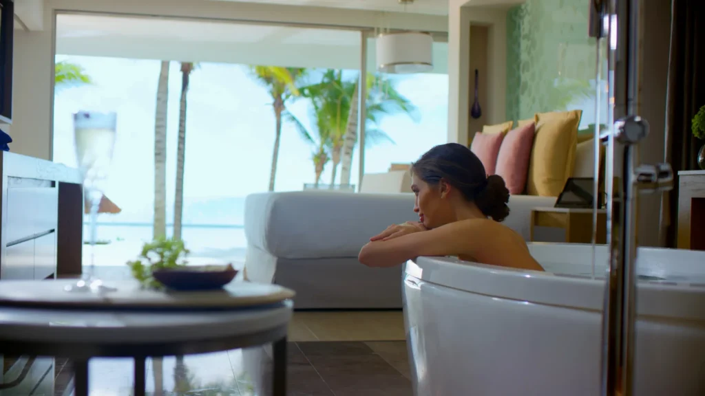 Guest relaxing in soaking tub inside Preferred Club Master Suite Swim Out Ocean Front at Secrets Riviera Cancun.