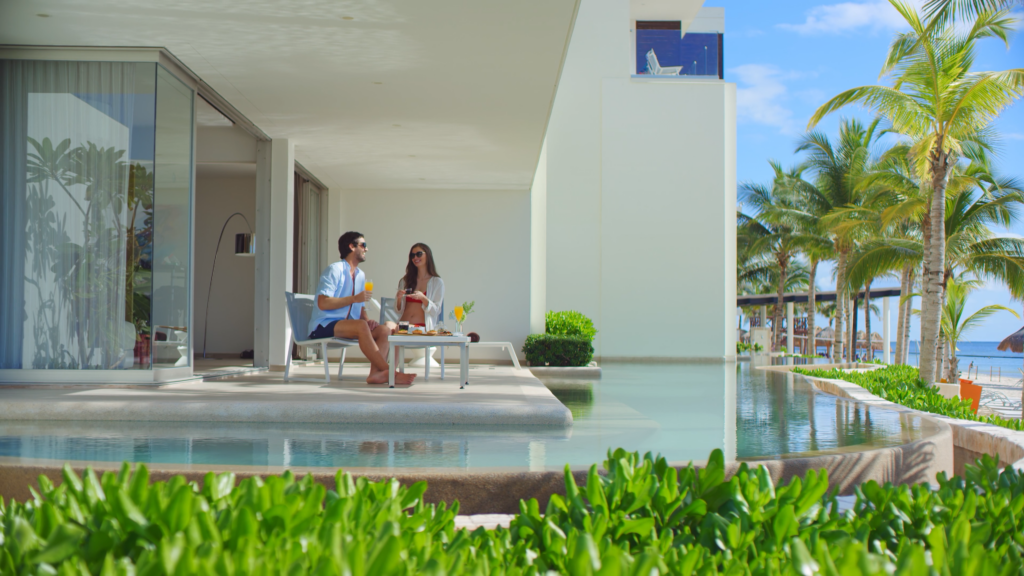 Couple relaxing on private terrace with swim-up pool at Secrets Riviera Cancun oceanfront suite.