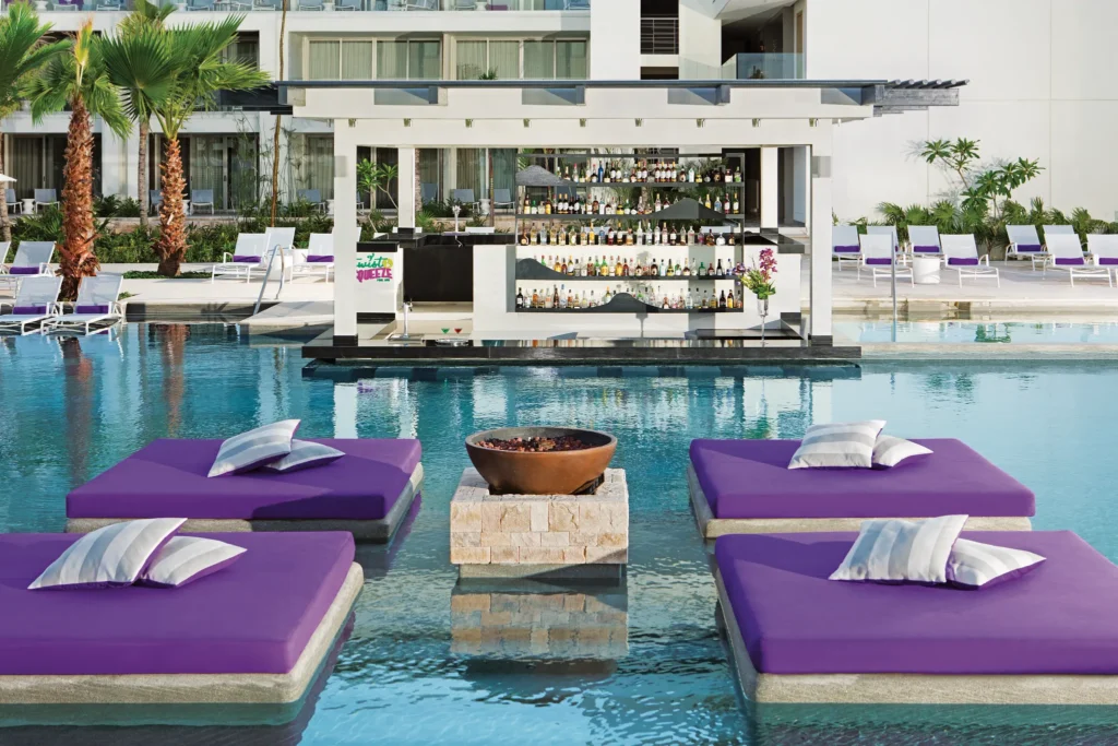 Twist & Squeeze Swim-Up Bar at Secrets Riviera Cancun featuring poolside lounge beds and refreshing tropical cocktails.